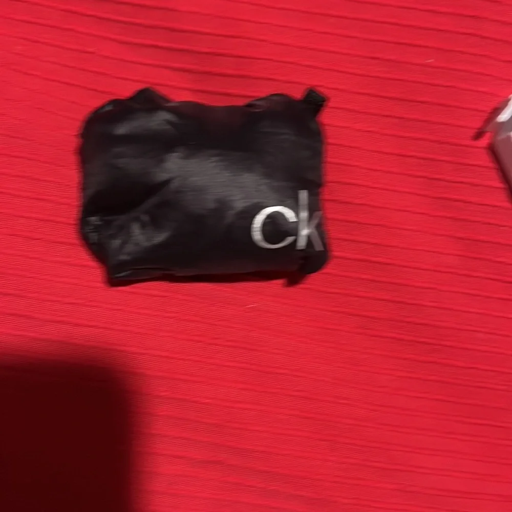 CK black draw string bag, used but great condition. Black and silver 12” x 5”